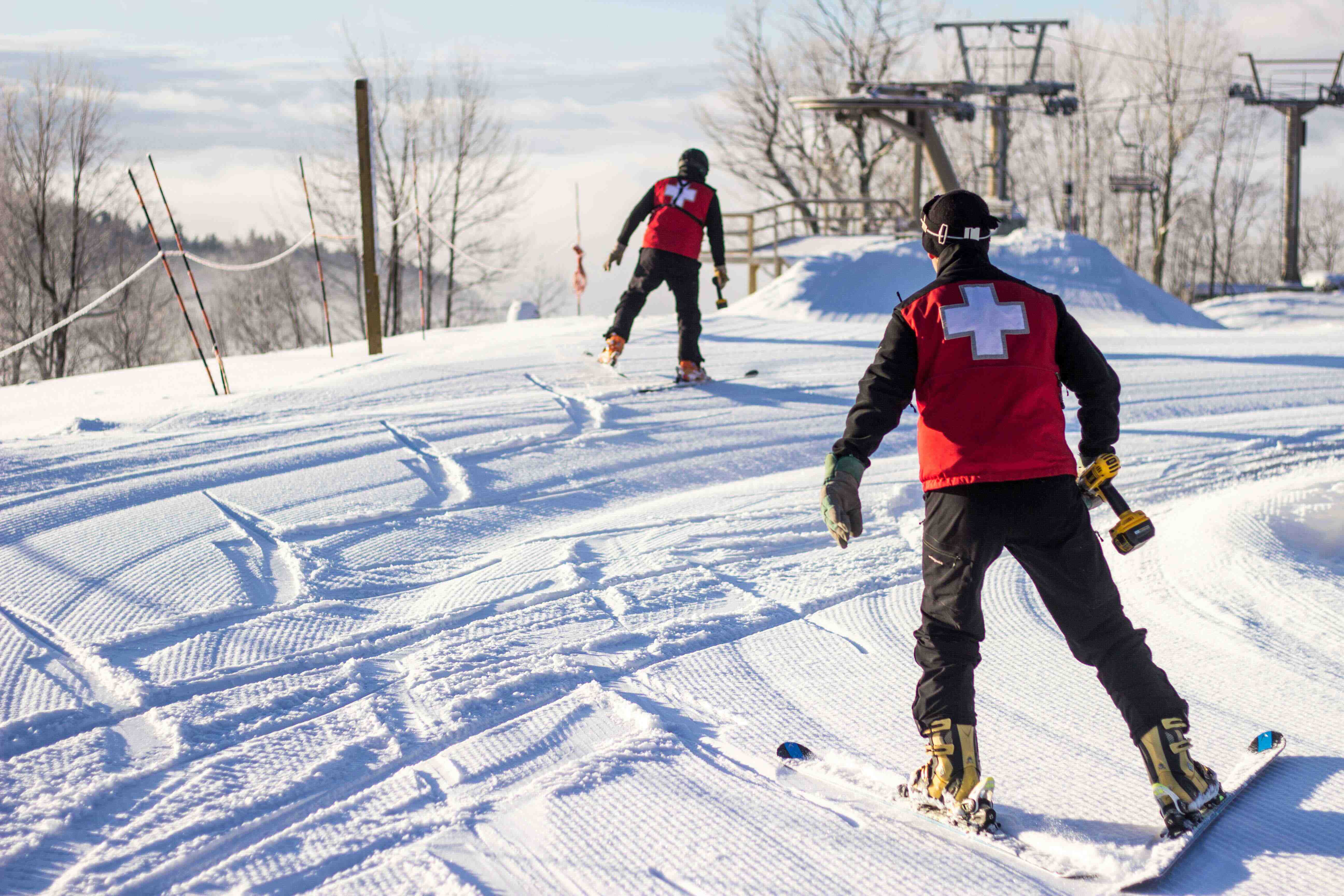 Two ski patrol skiing towards lift