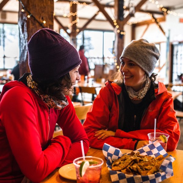 Ladies in red jackets and beanies with food and drinks at table