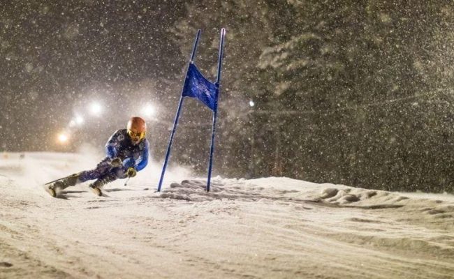 racer at night in the snow turning around blue gate