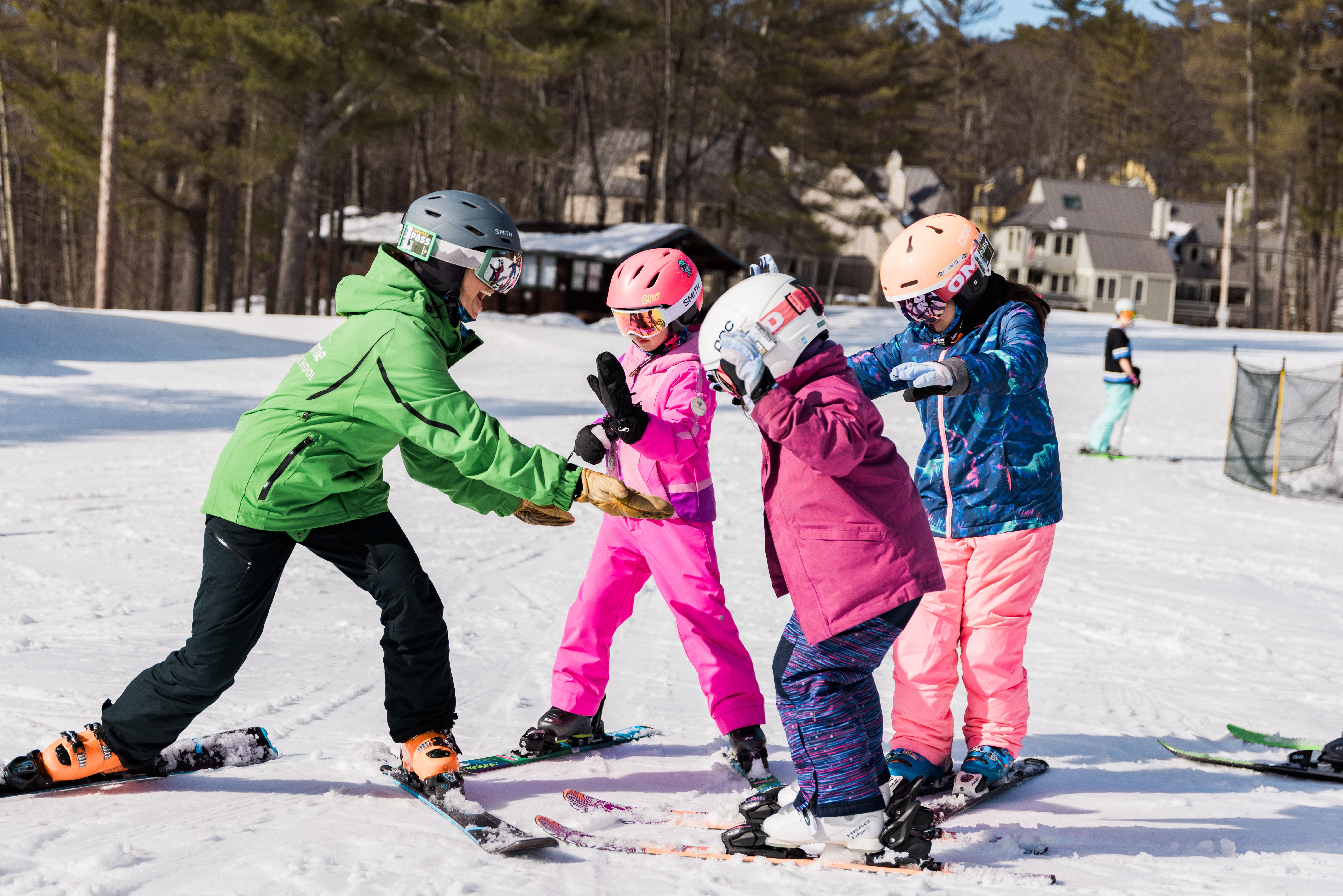 Instructor on skis with three kids learning to ski