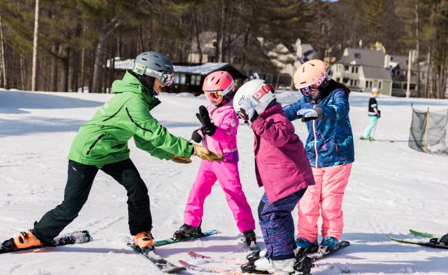 Instructor on skis with three kids learning to ski